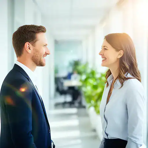 Due colleghi che interagiscono positivamente in un ambiente di lavoro luminoso e ben organizzato.